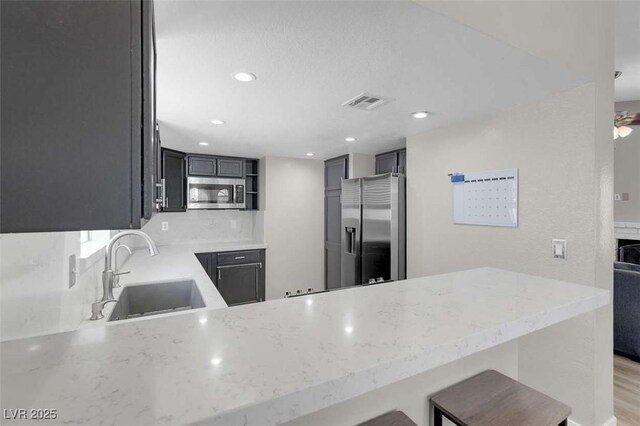 1622 Lorna Dr, Henderson, NV 89011 - kitchen with a sink, stainless steel appliances, a peninsula, light stone counters, and backsplash