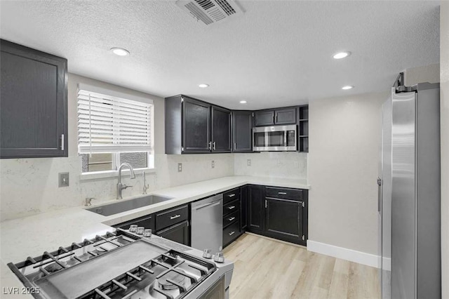 1622 Lorna Dr, Henderson, NV 89011 - kitchen featuring stainless steel appliances, a sink, light wood-style flooring, backsplash, and a textured ceiling