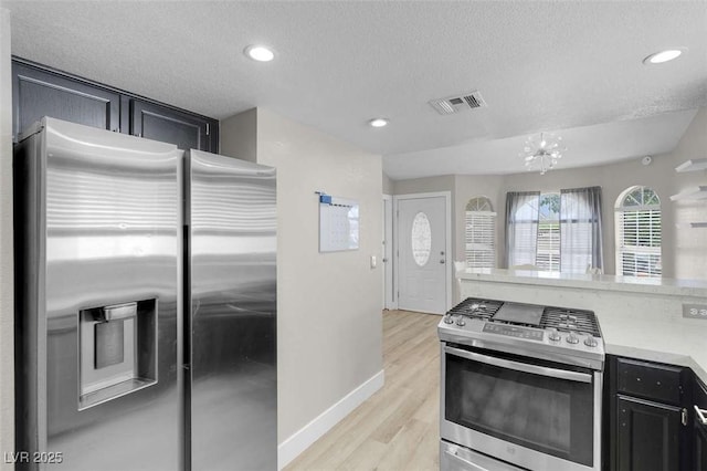 1622 Lorna Dr, Henderson, NV 89011 - kitchen with appliances with stainless steel finishes, a textured ceiling, light countertops, light wood-type flooring, and dark cabinets