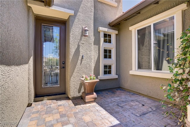 doorway to property featuring stucco siding and a patio area