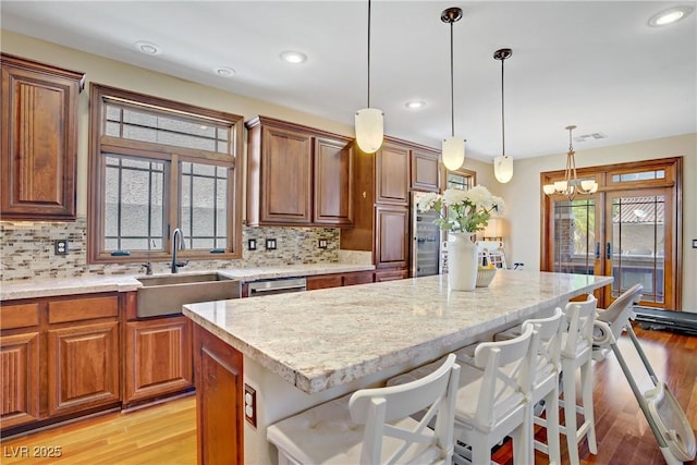 kitchen with light stone countertops, a sink, light wood-type flooring, and recessed lighting