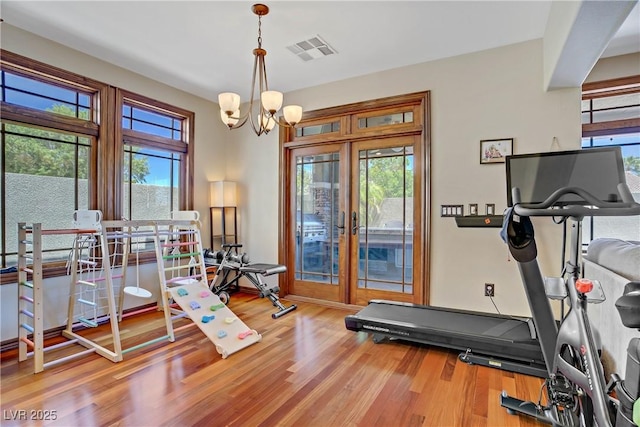 workout room featuring french doors, wood finished floors, and a chandelier