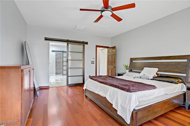 10520 Maystar Ln, Las Vegas, NV 89135 - bedroom featuring a barn door, wood finished floors, and a ceiling fan