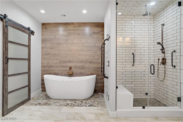 bathroom with recessed lighting, a freestanding bath, a stall shower, and marble finish flooring