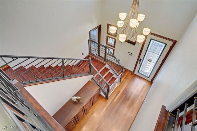 foyer entrance with wood finished floors, stairs, a high ceiling, and a chandelier