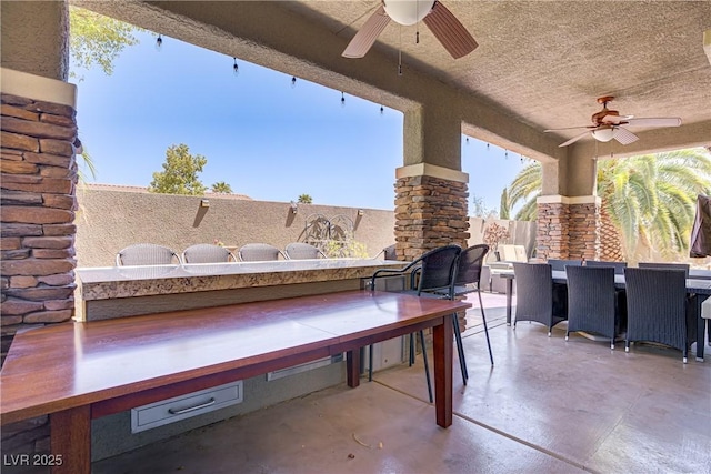 view of patio with outdoor dining space, a ceiling fan, and fence