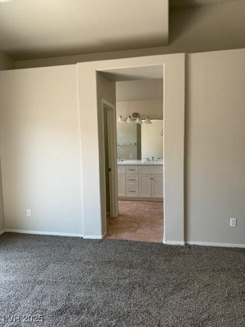 unfurnished bedroom featuring carpet flooring, a sink, baseboards, and ensuite bathroom