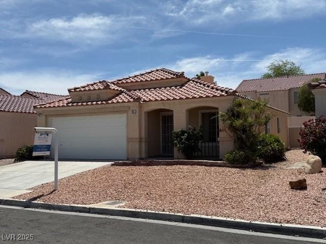 mediterranean / spanish house with driveway, stucco siding, a garage, and a tile roof