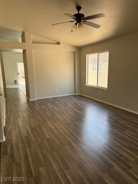 unfurnished room with dark wood-style flooring, ceiling fan, baseboards, and vaulted ceiling