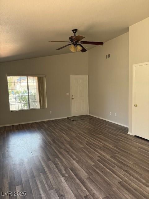 unfurnished living room with dark wood-type flooring, a ceiling fan, and baseboards