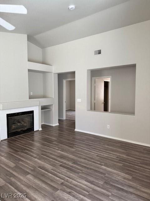 unfurnished living room featuring dark wood-style floors, baseboards, a tile fireplace, ceiling fan, and high vaulted ceiling