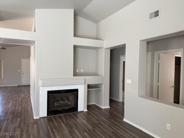 unfurnished living room with lofted ceiling, wood finished floors, baseboards, and a tiled fireplace