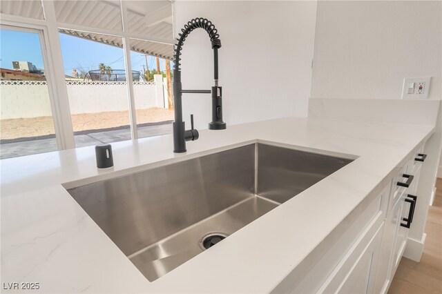6205 Hargrove Ave, Las Vegas, NV 89107 - kitchen view of a sink, white cabinetry, and light stone countertops