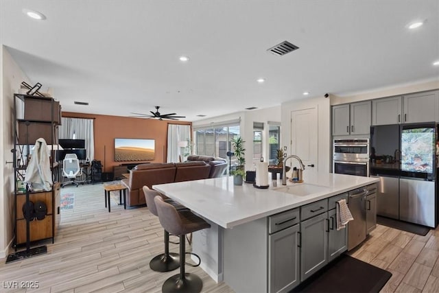 9710 Hiking Ave, Las Vegas, NV 89166 - kitchen with stainless steel appliances, gray cabinetry, a sink, light wood-style flooring, and recessed lighting