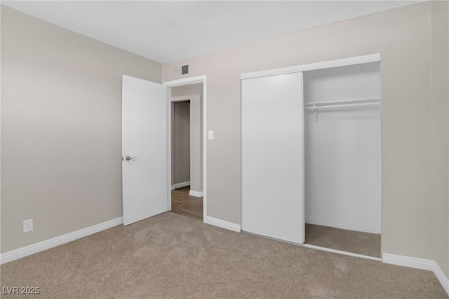 unfurnished bedroom with carpet floors, a closet, and baseboards
