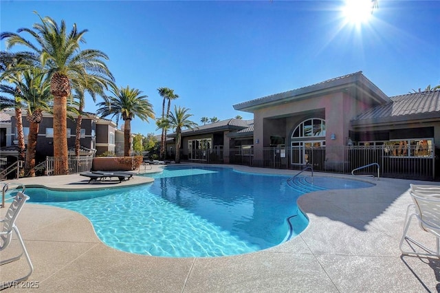 community pool with a patio area and fence