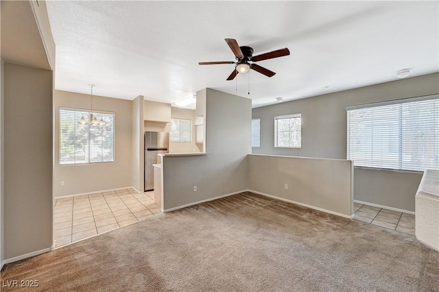 carpeted spare room featuring tile patterned flooring, ceiling fan, baseboards, and a chandelier