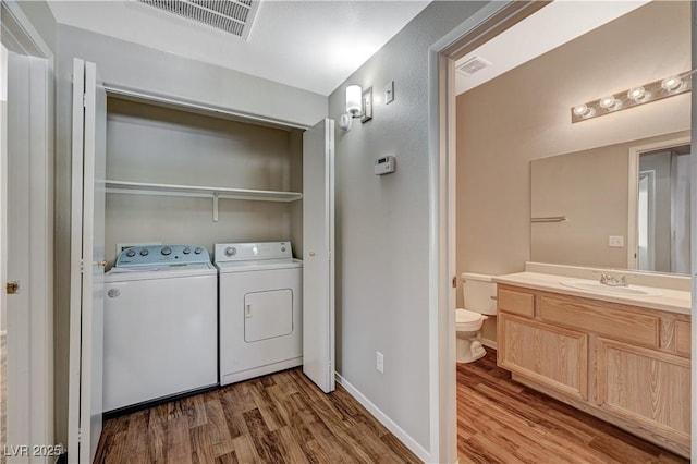 laundry area with wood finished floors, washing machine and clothes dryer, and baseboards