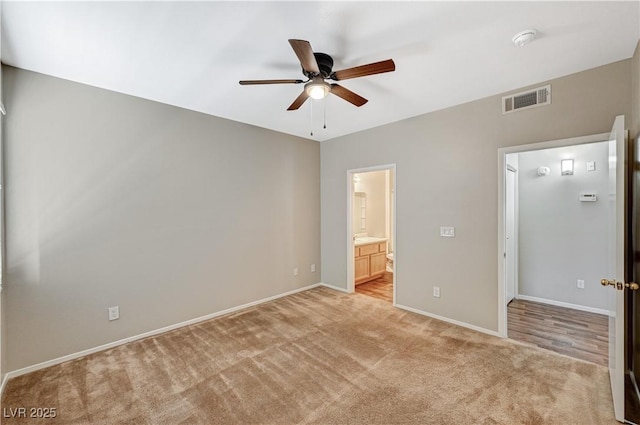 unfurnished bedroom featuring light carpet, baseboards, ensuite bath, and a ceiling fan