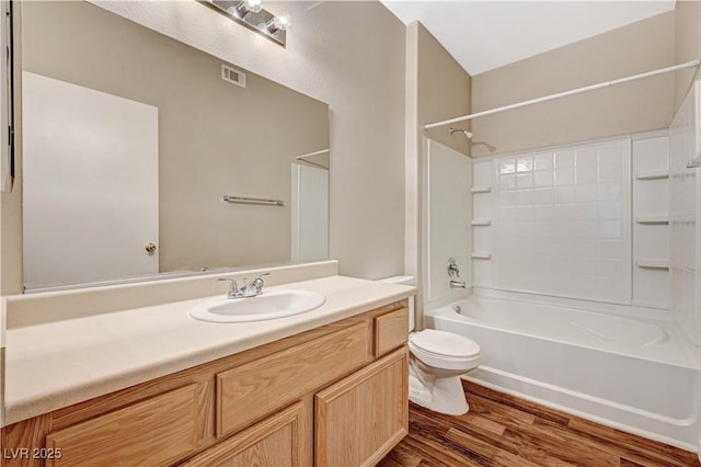 bathroom featuring wood finished floors, toilet, vanity, and bathtub / shower combination