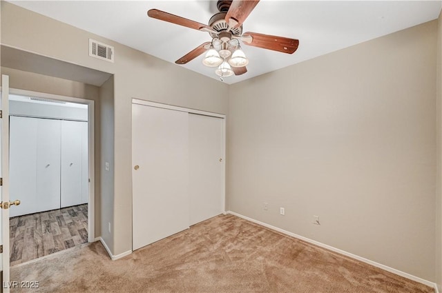 unfurnished bedroom with carpet floors, a closet, baseboards, and a ceiling fan