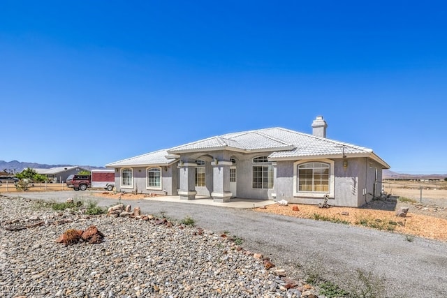 1410 Tiptop Trl, Pahrump, NV 89048 - view of front facade with a chimney, fence, stucco siding, and a tile roof