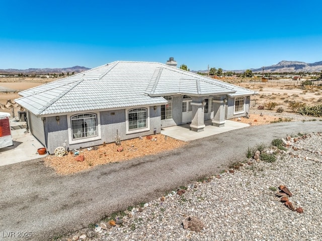 1410 Tiptop Trl, Pahrump, NV 89048 - ranch-style home featuring a mountain view, a tiled roof, stucco siding, and a chimney