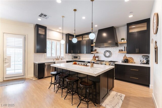 10002 Trapper Mountain St, Las Vegas, NV 89178 - kitchen featuring wall chimney range hood, dishwasher, open shelves, an island with sink, and a breakfast bar