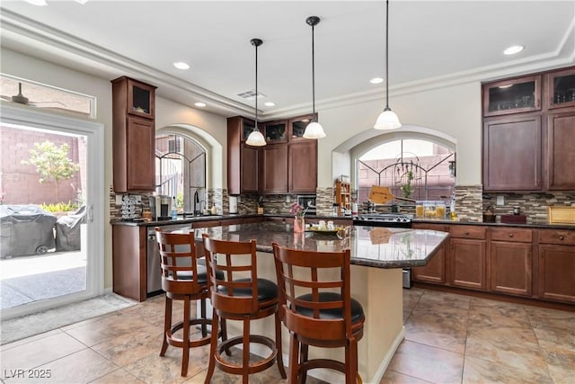 8275 Old Creek Ranch St, Las Vegas, NV 89139 - kitchen featuring a kitchen island, tasteful backsplash, recessed lighting, a breakfast bar area, and arched walkways