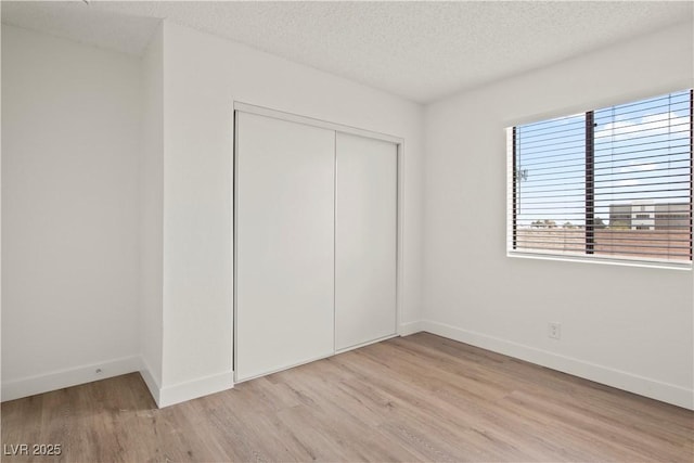 829 Rock Springs Dr Unit 201, Las Vegas, NV 89128 - unfurnished bedroom with light wood finished floors, a closet, baseboards, and a textured ceiling