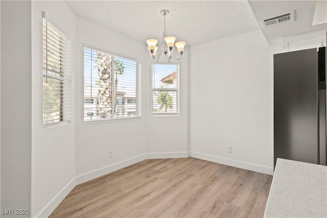 829 Rock Springs Dr Unit 201, Las Vegas, NV 89128 - unfurnished dining area featuring light wood-type flooring, a chandelier, a textured ceiling, and baseboards