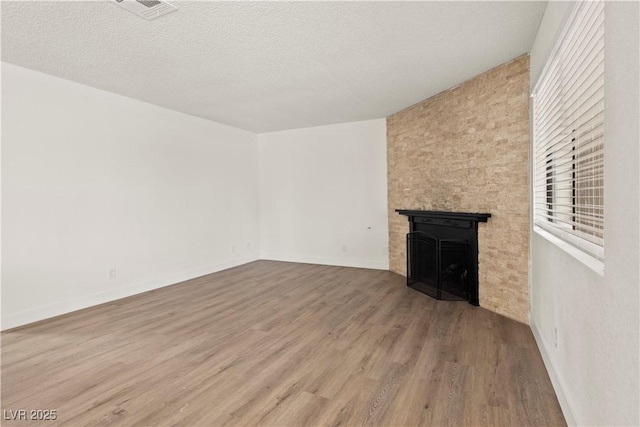 829 Rock Springs Dr Unit 201, Las Vegas, NV 89128 - unfurnished living room with a large fireplace, wood finished floors, a textured ceiling, and baseboards