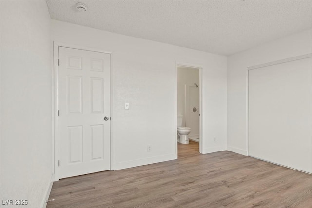 829 Rock Springs Dr Unit 201, Las Vegas, NV 89128 - unfurnished bedroom with wood finished floors, a textured ceiling, connected bathroom, and baseboards