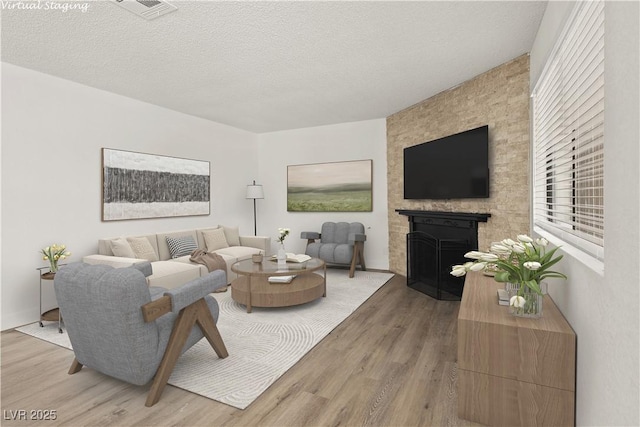 829 Rock Springs Dr Unit 201, Las Vegas, NV 89128 - living room featuring a fireplace, light wood-type flooring, and a textured ceiling