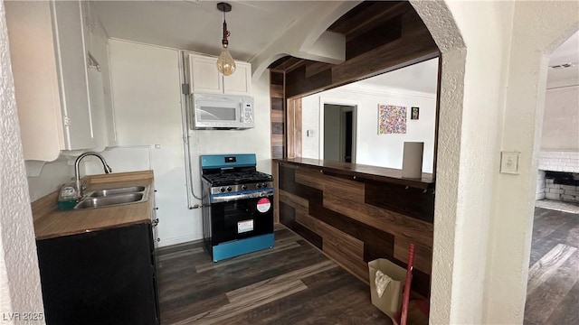 kitchen with white microwave, stainless steel gas range, a sink, dark wood-style flooring, and white cabinets