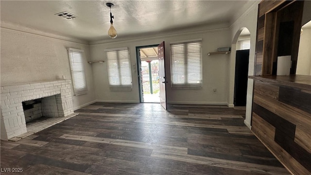 unfurnished living room with wood finished floors, baseboards, arched walkways, and crown molding