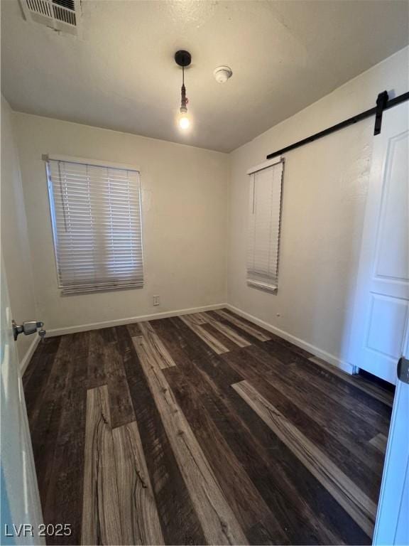 empty room with wood finished floors, baseboards, and a barn door