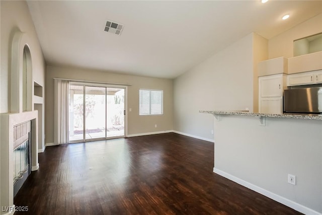 3416 Steppe St, North Las Vegas, NV 89032 - unfurnished living room with vaulted ceiling, baseboards, a glass covered fireplace, dark wood-type flooring, and recessed lighting