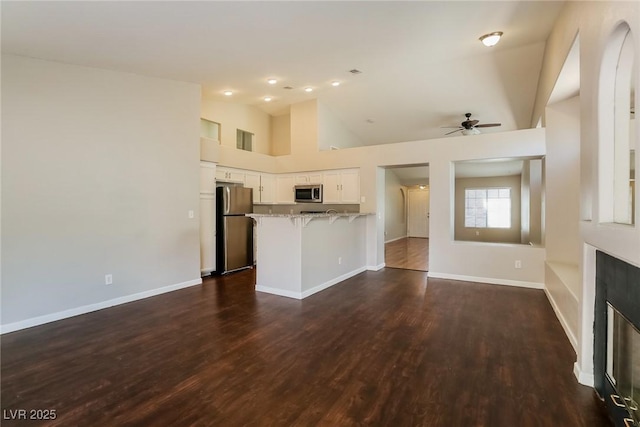 3416 Steppe St, North Las Vegas, NV 89032 - unfurnished living room with ceiling fan, dark wood-style floors, baseboards, a glass covered fireplace, and lofted ceiling