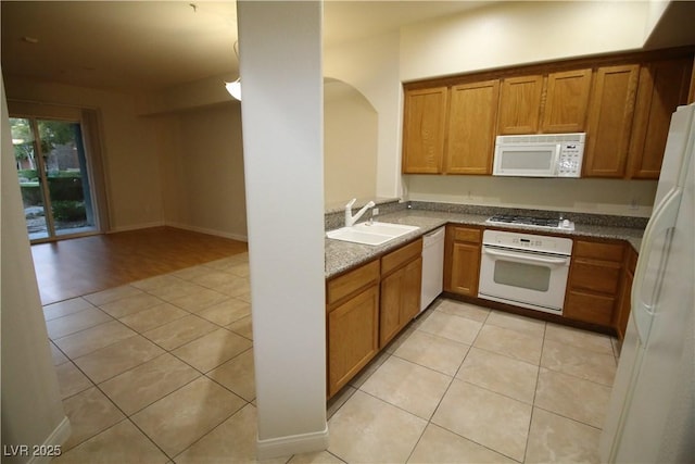62 E Serene Ave Unit 129, Las Vegas, NV 89123 - kitchen featuring white appliances, a sink, brown cabinetry, and light tile patterned flooring