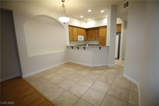 62 E Serene Ave Unit 129, Las Vegas, NV 89123 - kitchen with white microwave, light tile patterned floors, recessed lighting, hanging light fixtures, and a kitchen bar