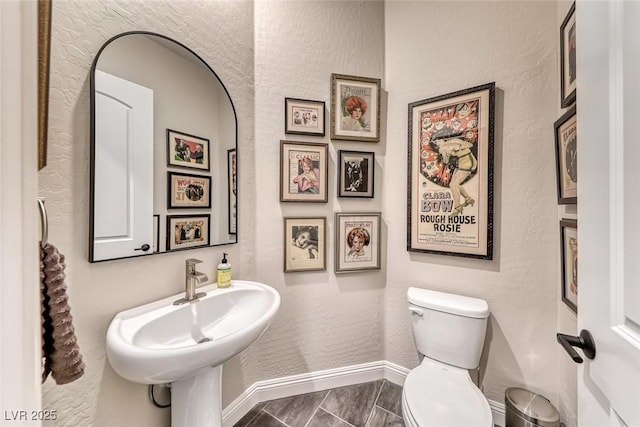 125 Mirage View Dr, Henderson, NV 89011 - bathroom featuring baseboards, toilet, a textured wall, a sink, and marble look tile flooring