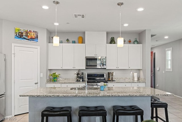 kitchen featuring stainless steel appliances, light tile patterned floors, a kitchen breakfast bar, white cabinets, and recessed lighting