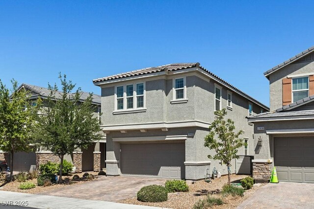 view of front of house with stucco siding, an attached garage, decorative driveway, and a tile roof