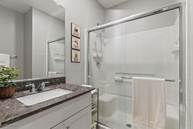 full bathroom featuring a textured wall, a shower stall, and vanity