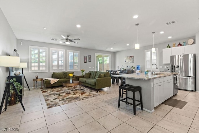kitchen featuring stainless steel refrigerator with ice dispenser, a sink, light tile patterned flooring, recessed lighting, and white cabinetry