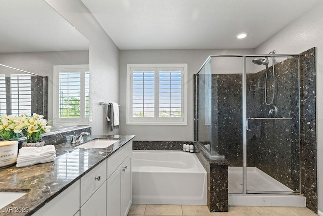 full bathroom with tile patterned floors, healthy amount of natural light, a garden tub, double vanity, and recessed lighting