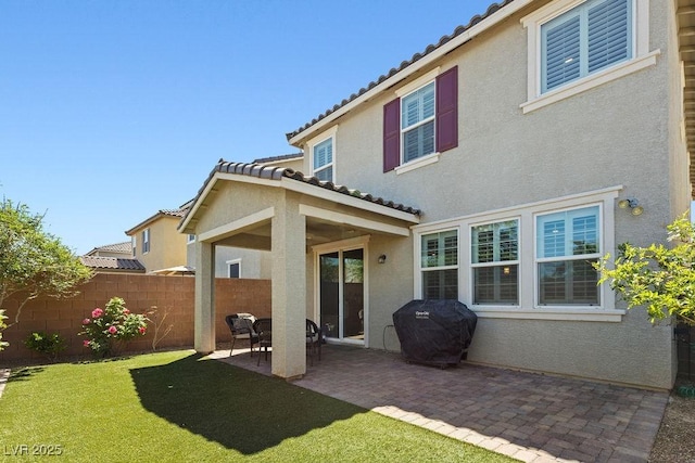 rear view of house with stucco siding, a tiled roof, and a patio area
