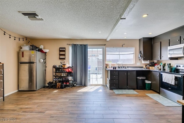 kitchen with stainless steel appliances, a textured ceiling, a sink, light wood-style flooring, and recessed lighting