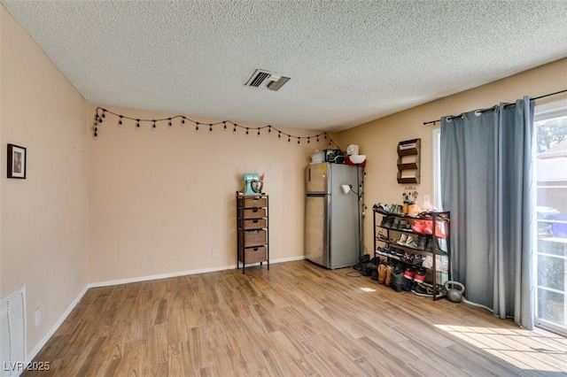 unfurnished room with light wood-style flooring, a textured ceiling, and baseboards